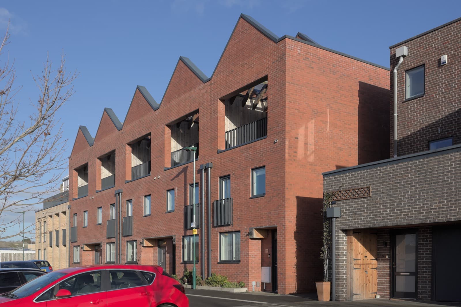 A row of modern red-brick terraced houses with pitched roofs on a clear day in Nottingham.
